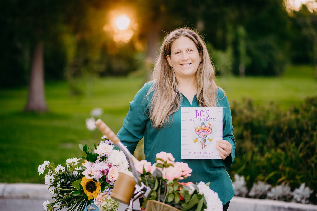 Christine Gurekian, author and Beau Blooms florist, holding her book in a garden