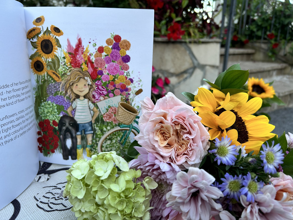 Open page of Bo's Bike of Blooms surrounded by fresh roses, sunflowers and asters