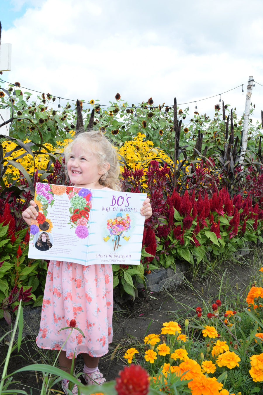Little girl holding Bo's Bike of Blooms in a flower garden