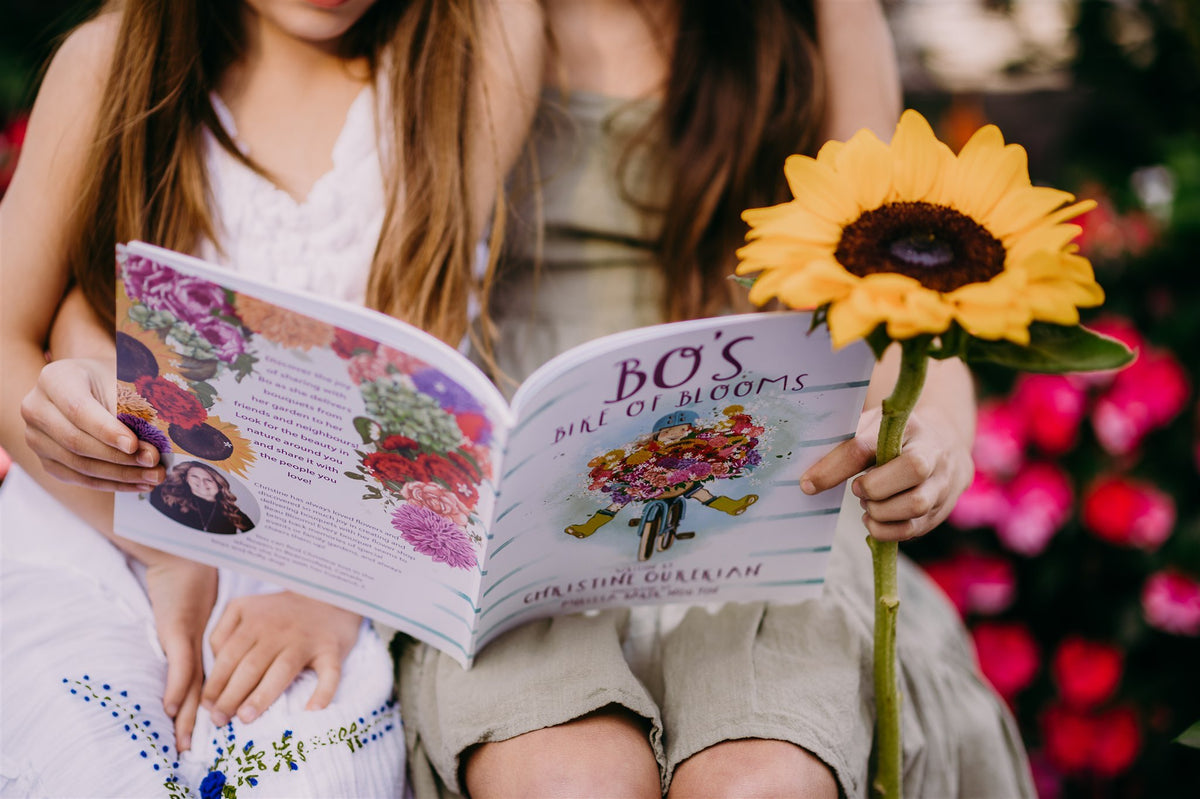 Open copy of Bo's Bike of Blooms held next to a sunflower